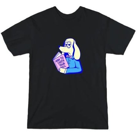Black T-shirt with a tan-colored dog in a blue shirt with a pink bowtie, holding a pink book that reads &quot;How To Catch Your Tail&quot;.