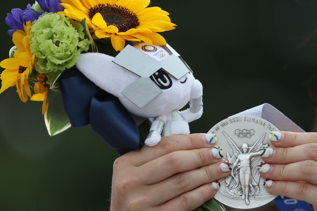 An Olympic athlete holding their silver medal and flowers