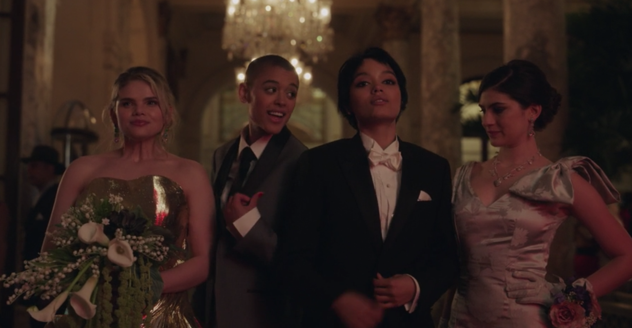 Pippa wears a strapless gown, Julien wears a light colored suit, Zoya wears a dark colored suit, and Bianca wears a tank top gown with a giant bow on the shoulder