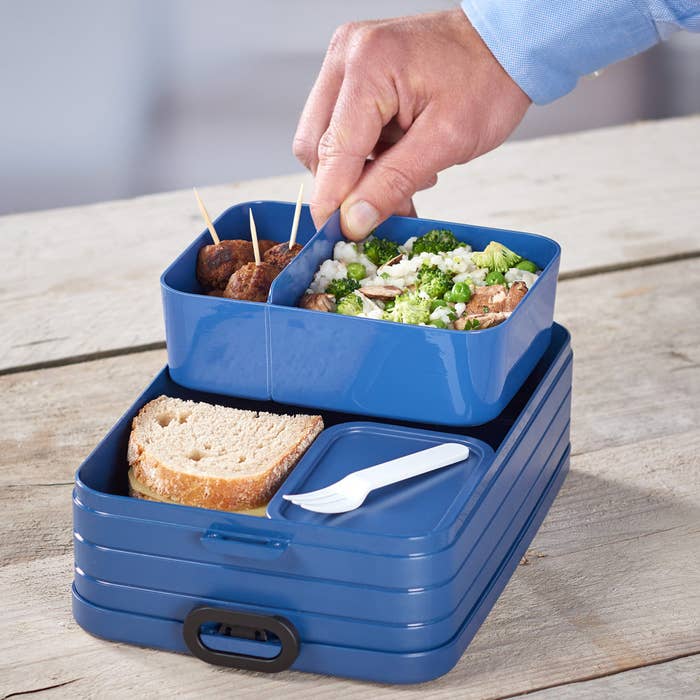 a person pulling out one of the compartments of the bento box lunch box