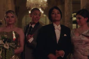 Bianca wears a strapless sparkly gown, Julien wears a light colored suit, Zoya wears a dark colored suit, and Pippa wears a tank top gown with a giant bow on the shoulder