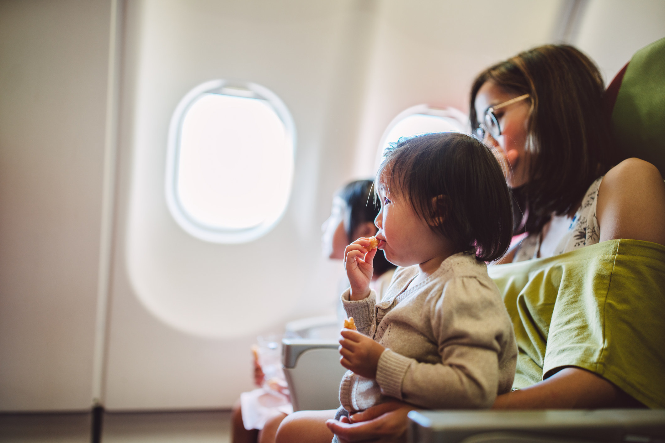 A mom feeding her baby on an airplane