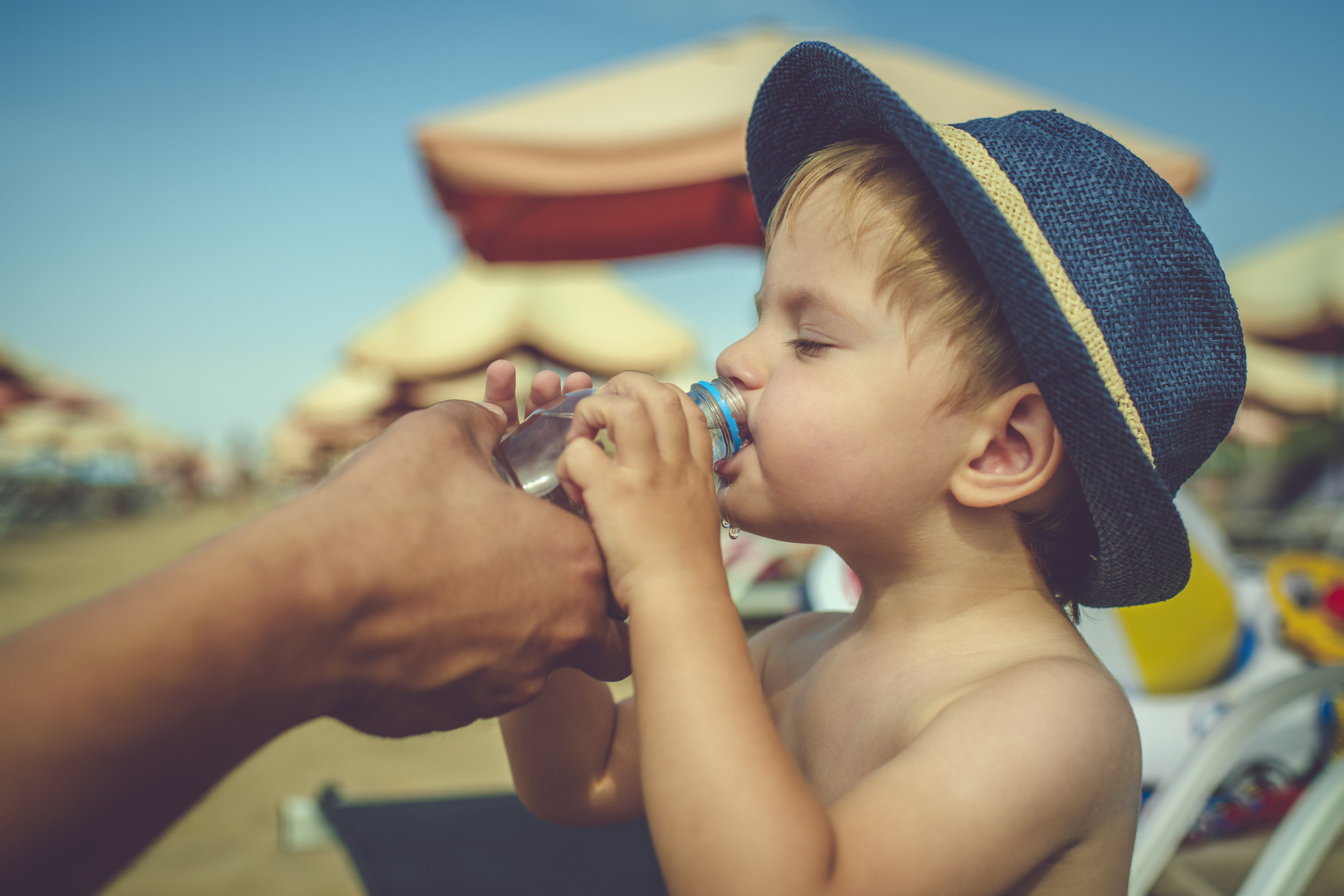 A young boy drinking water at the beach