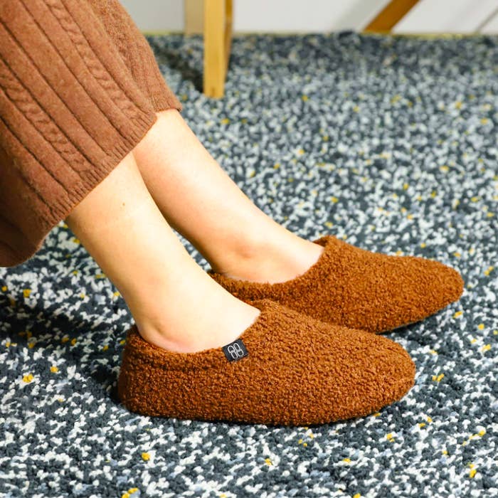 A person wearing the slippers on a carpet