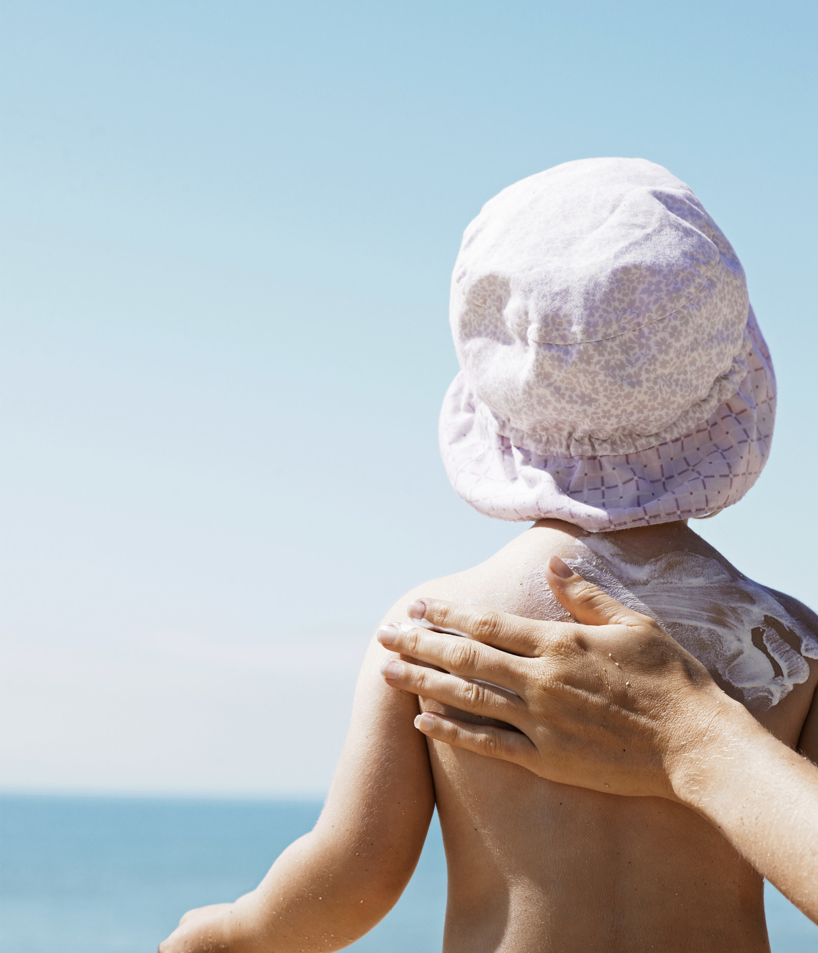 A mom applying sunscreen to her toddler