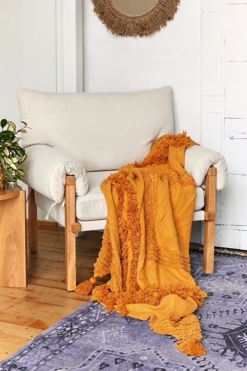 an accent chair with an orange tufted throw blanket