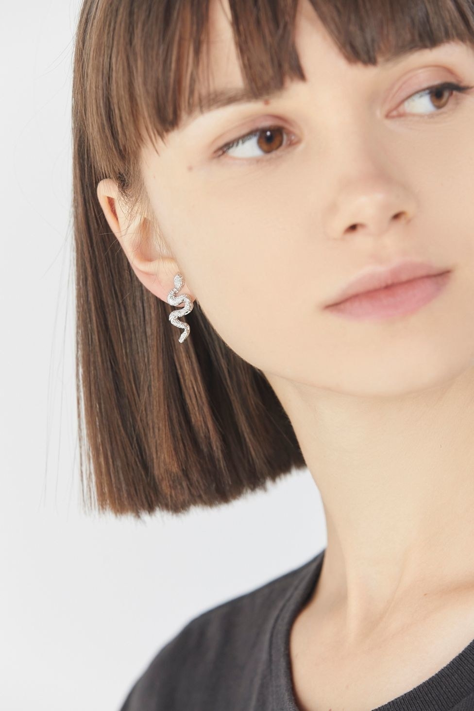 silver snake post earrings in a woman&#x27;s earlobe