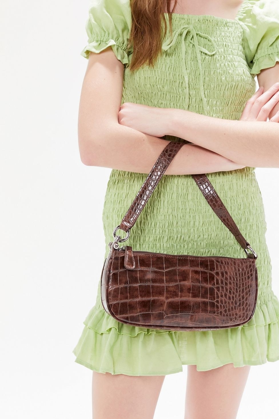 a woman holding a faux crocodile handbag