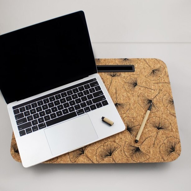 a laptop and pen on top of the cork laptop desk