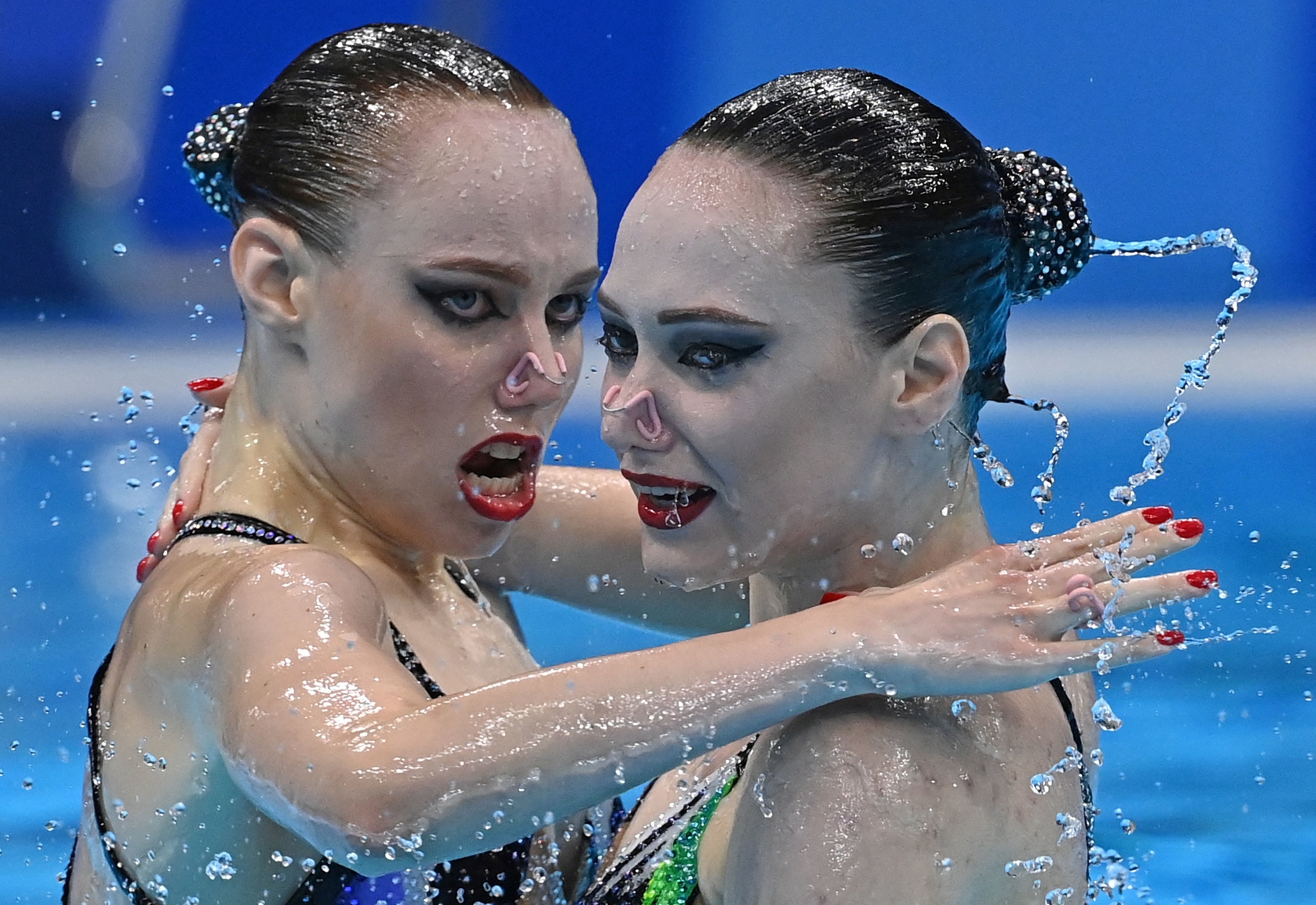 Two women swimmers have arms around each other in the pool at the Tokyo Olympics