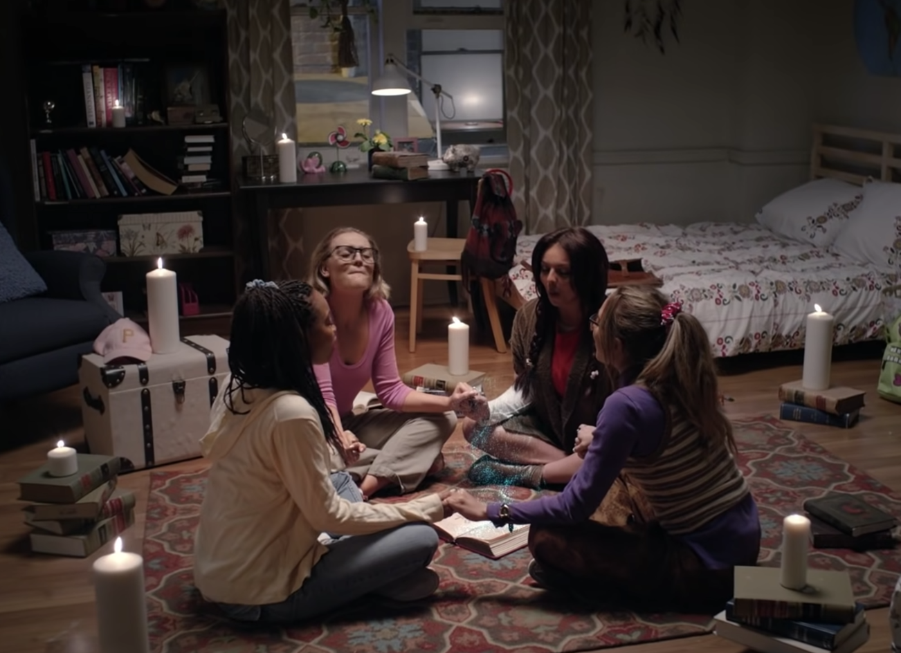 The girls holding hands and doing a spell in the music video