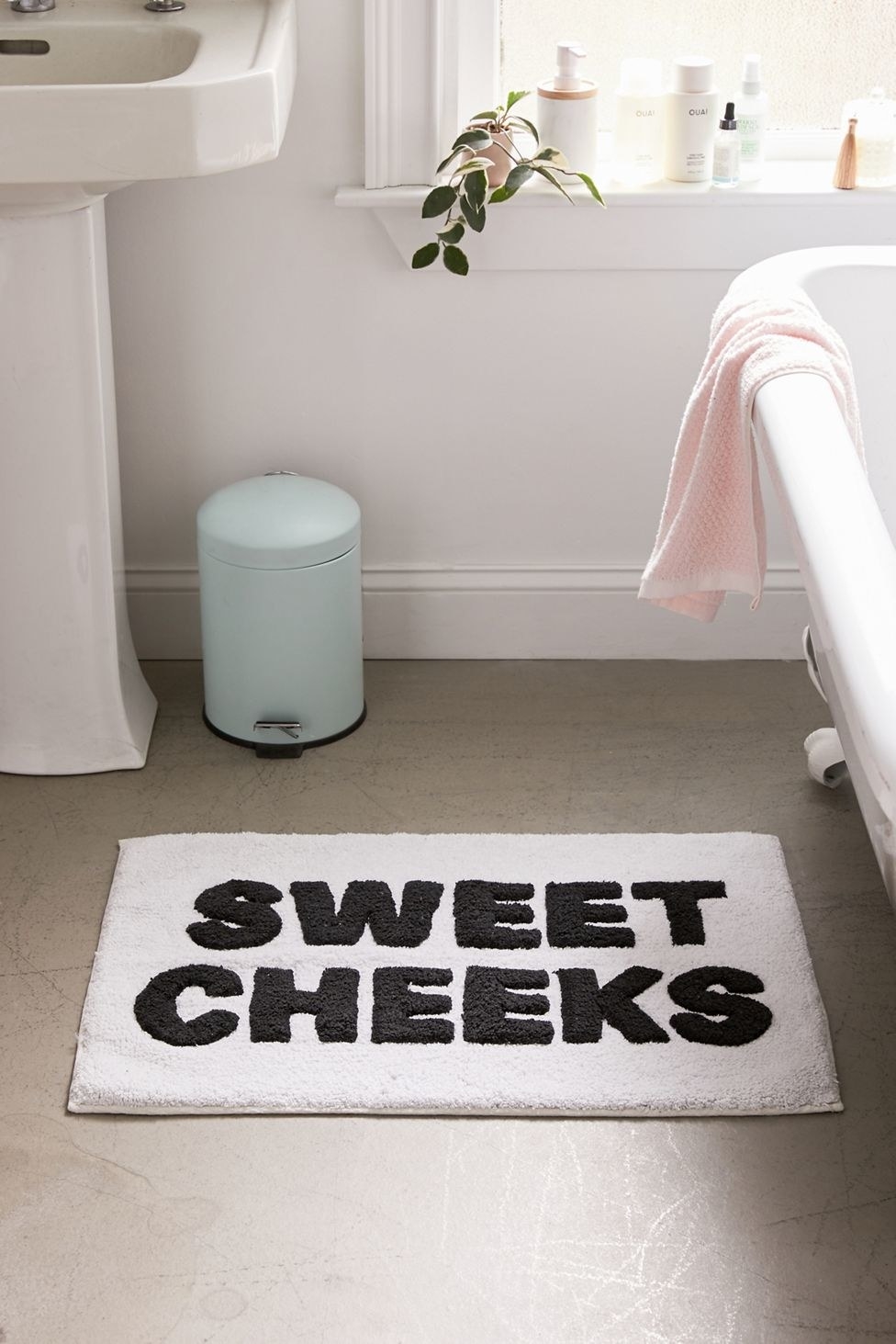 a white bath mat that reads &quot;sweet cheeks&quot; in black uppercase letters