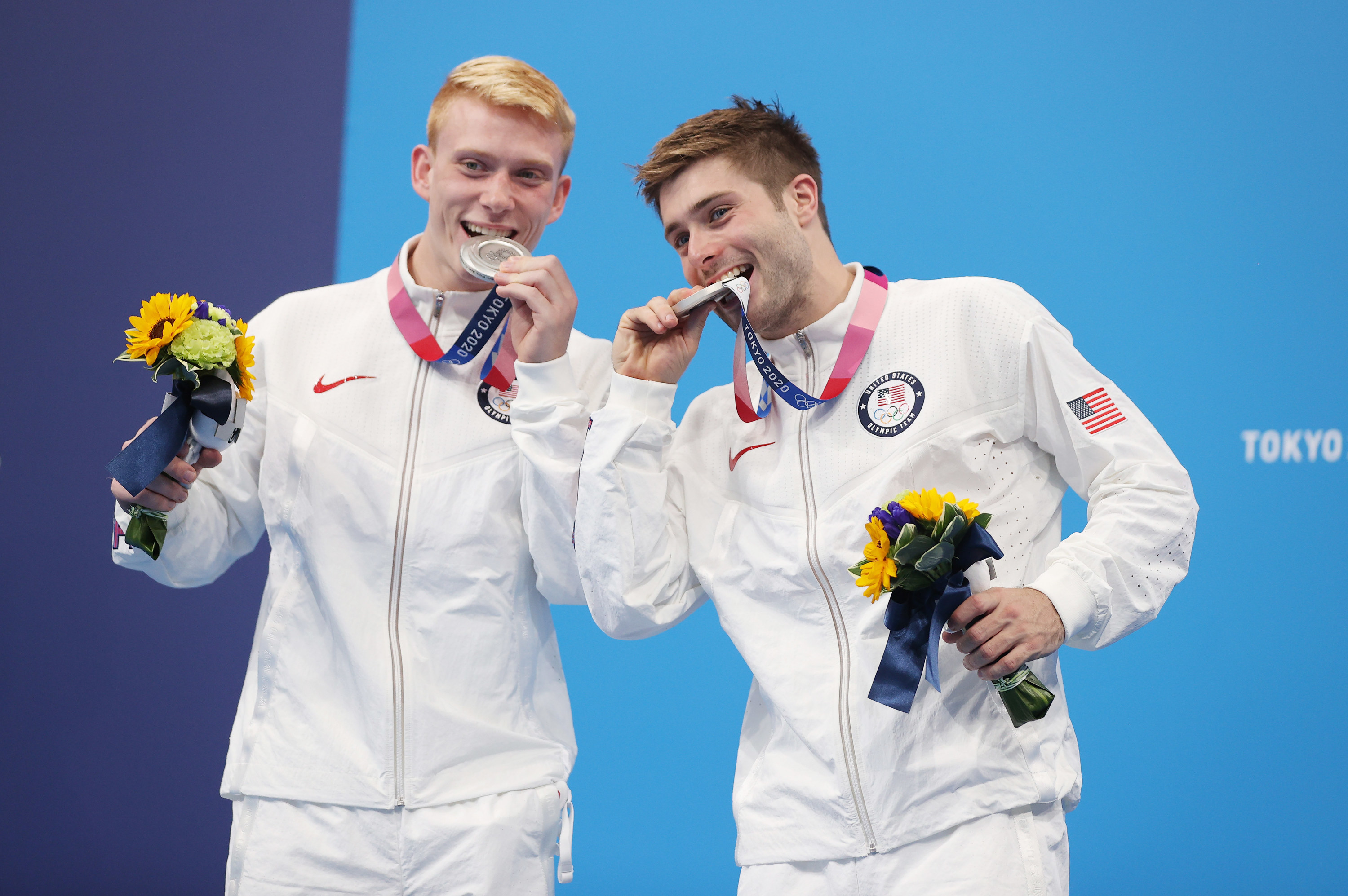 Andrew Capobianco and his diving partner pose biting their medals after win...