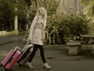 A woman rolling pink luggages