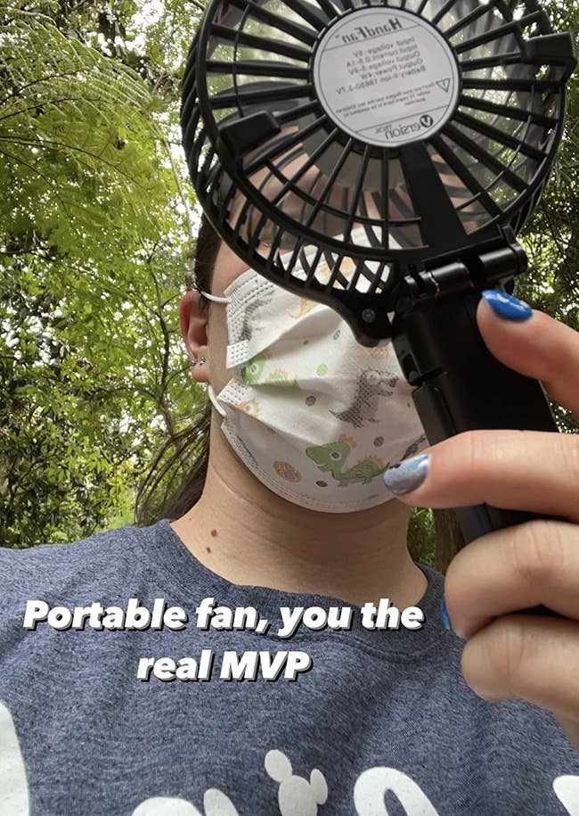 reviewer holding the black small fan with the words 