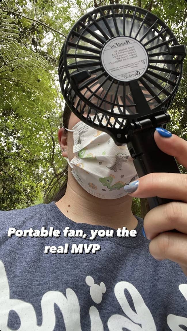 reviewer holding the black small fan with the words 