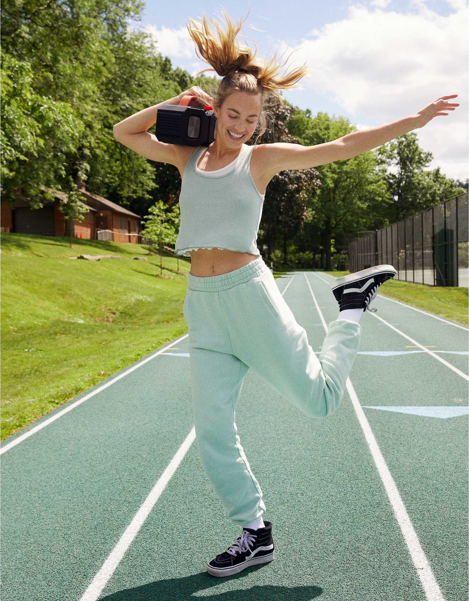 girl in sea foam green joggers and running on a track