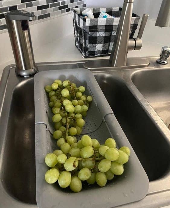 A customer review photo of them using the over-the-sink strainer to wash grapes