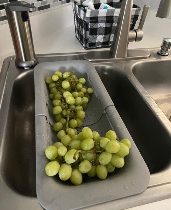 reviewer using the over-the-sink strainer to wash grapes