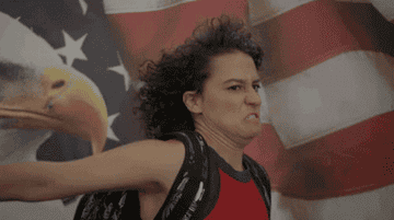 Ilana from Broad City giving a salute in front of an American flag