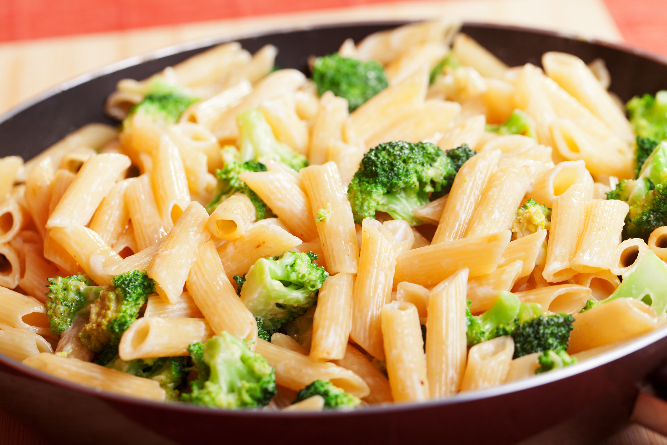 A skillet of penne and broccoli.