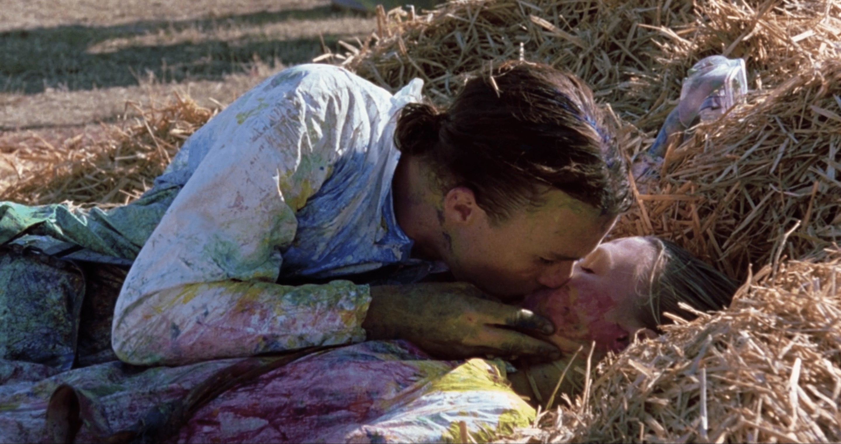 Kat and Patrick kiss in the hay after a game of paintball