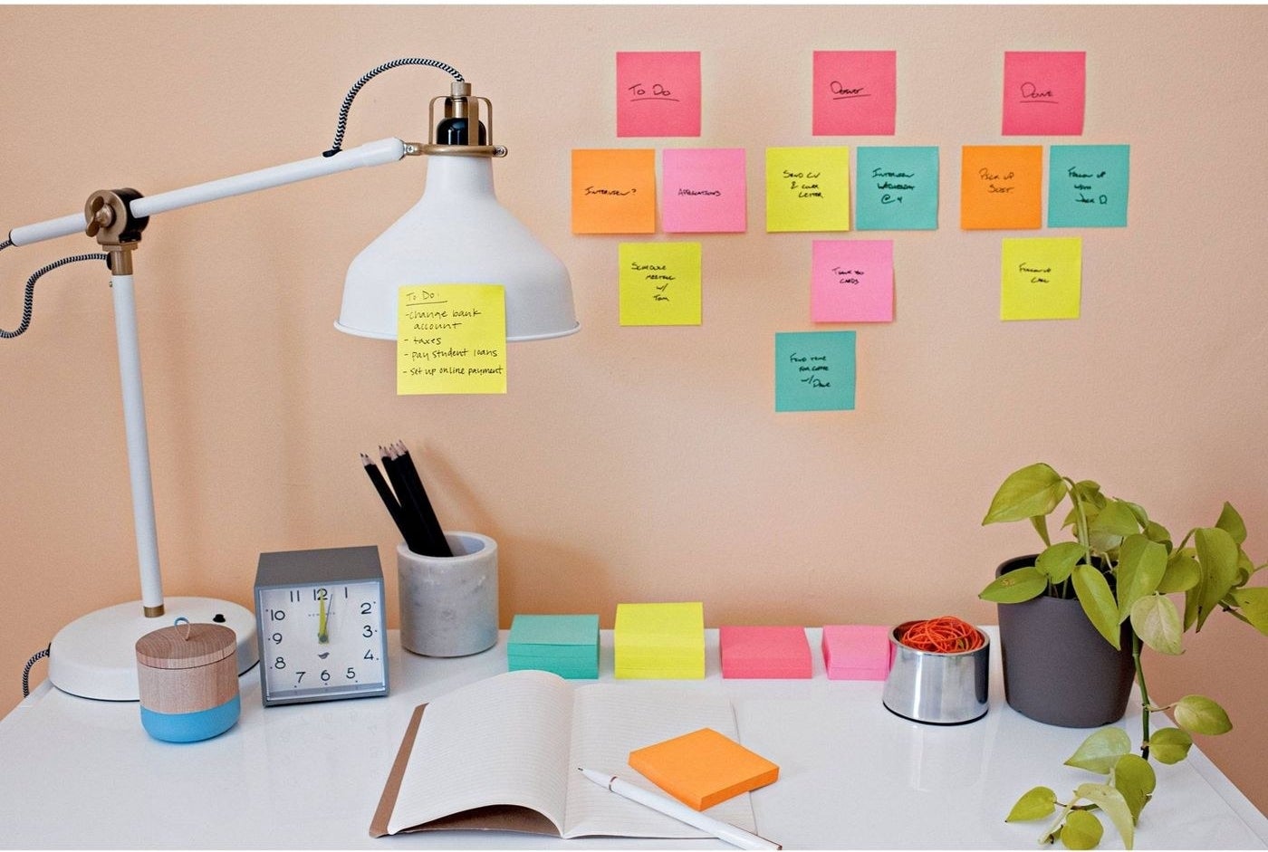 desk with stacks of colorful post-it note pads and post-its on the wall