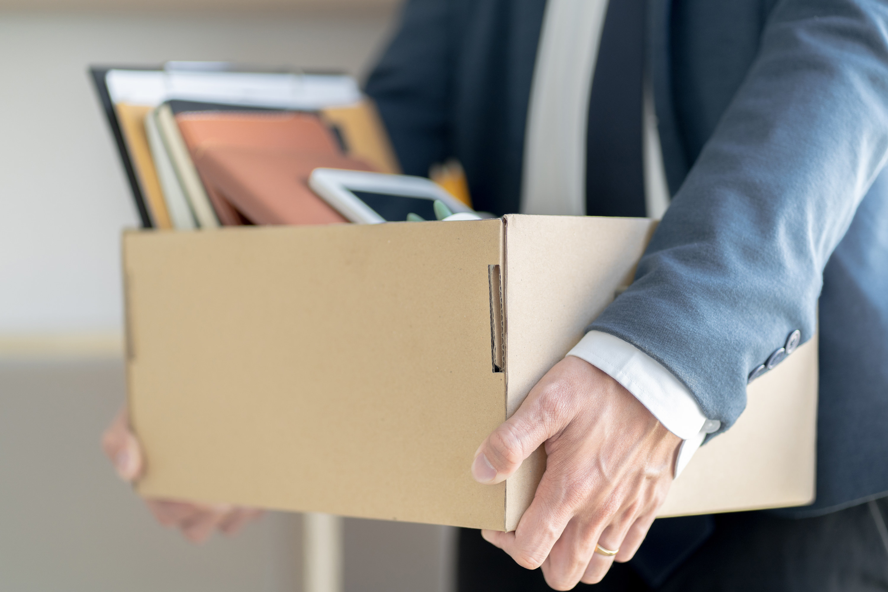 Person carrying a box of their things out of the office after being fired