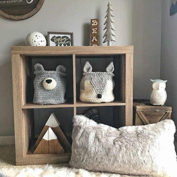 The grey crochet fox basket displayed in a wooden cube storage unit in a nursery
