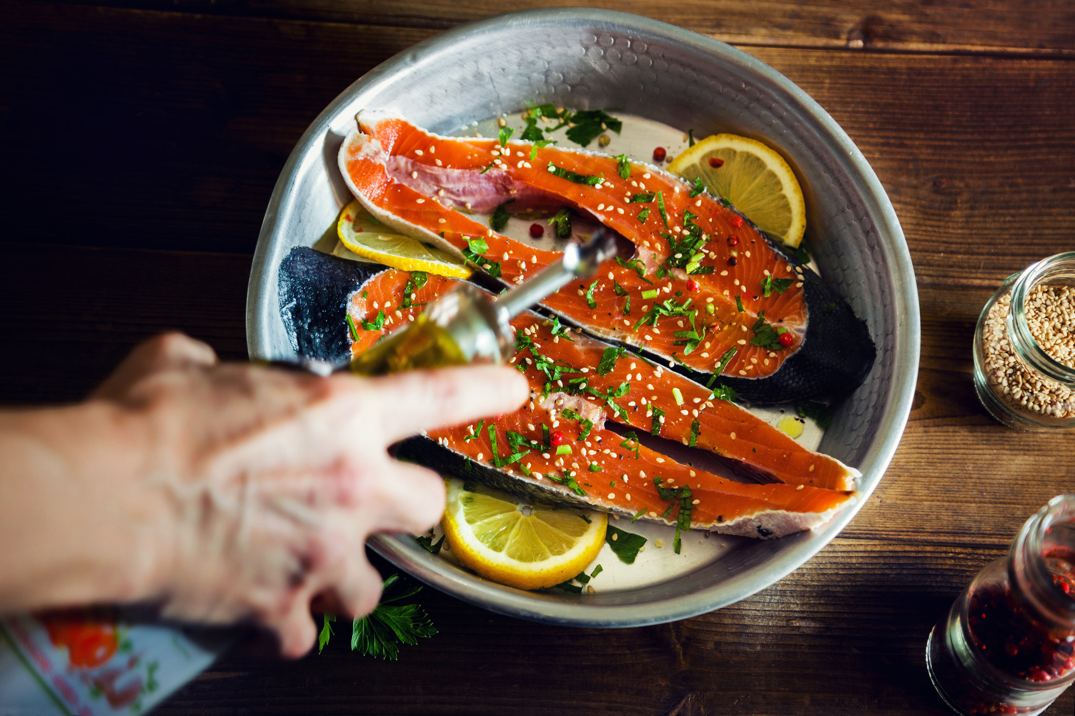 Drizzling oil onto salmon.