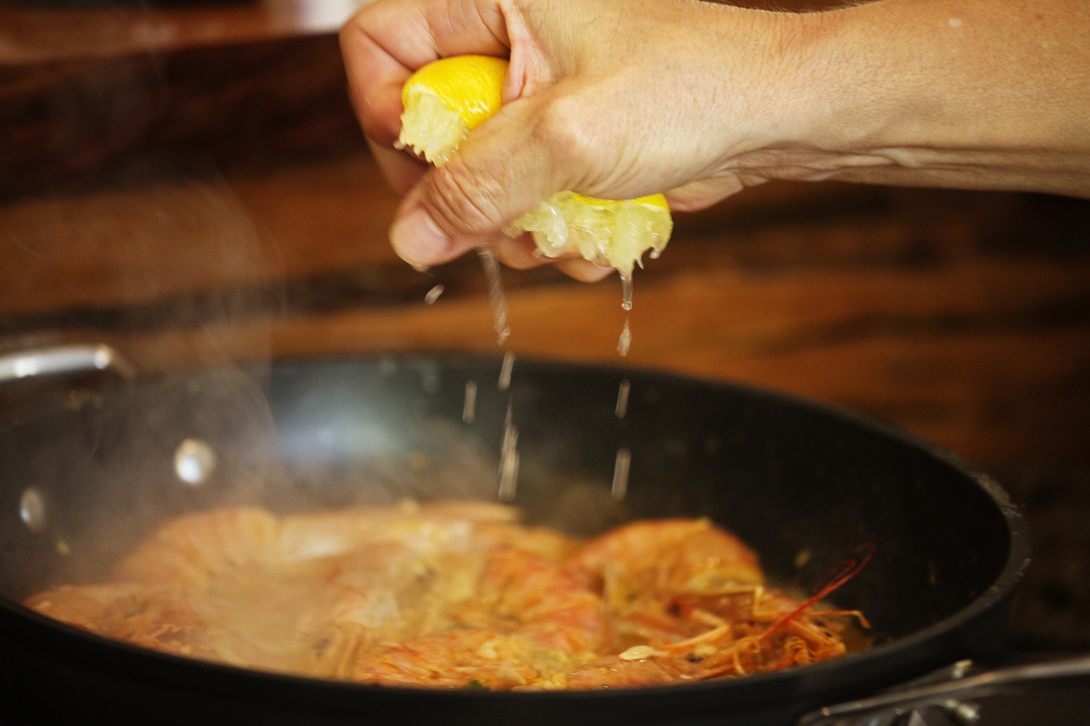 Squeezing lemon juice into a pan.