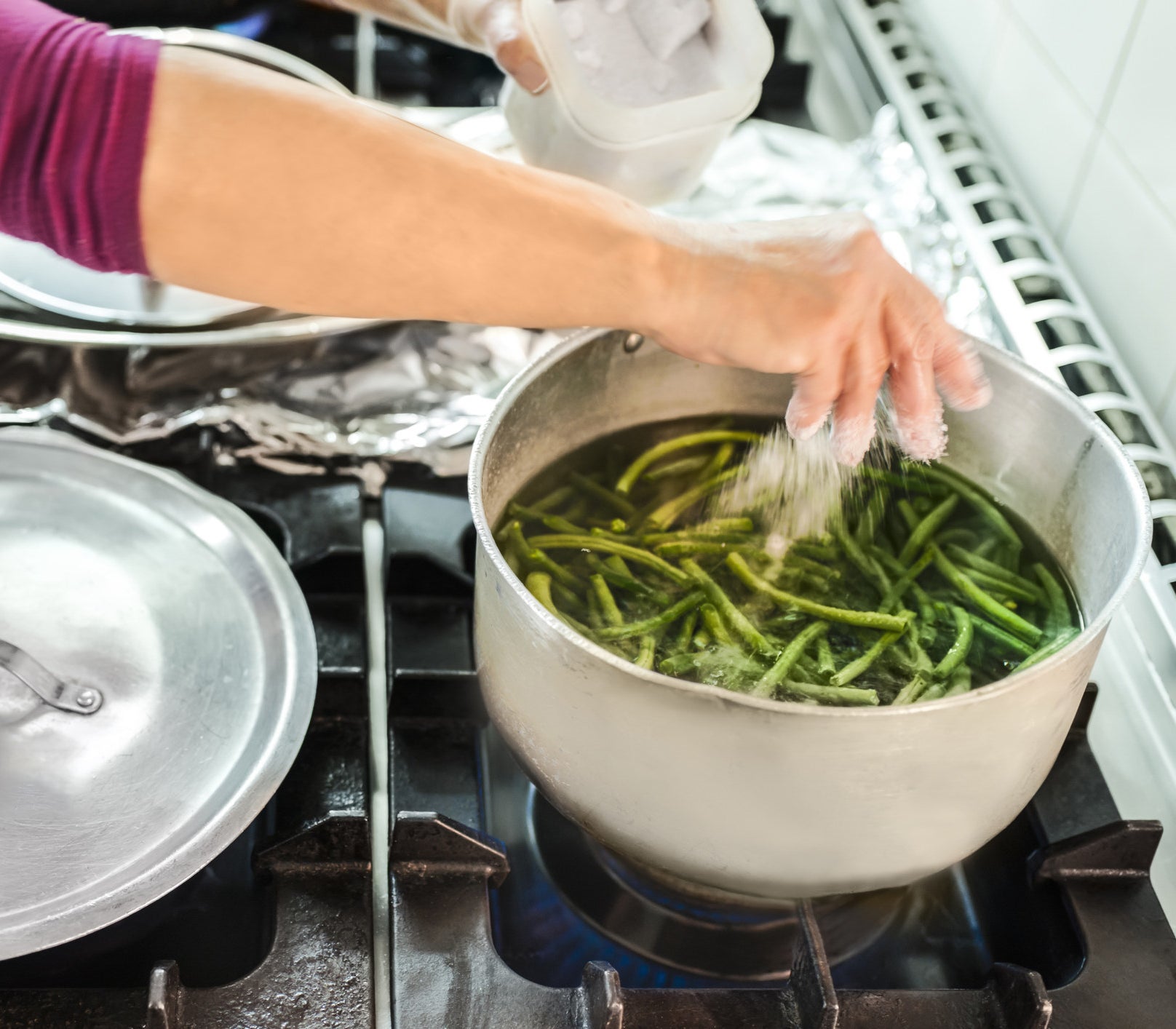 Salting green beans in a pot.