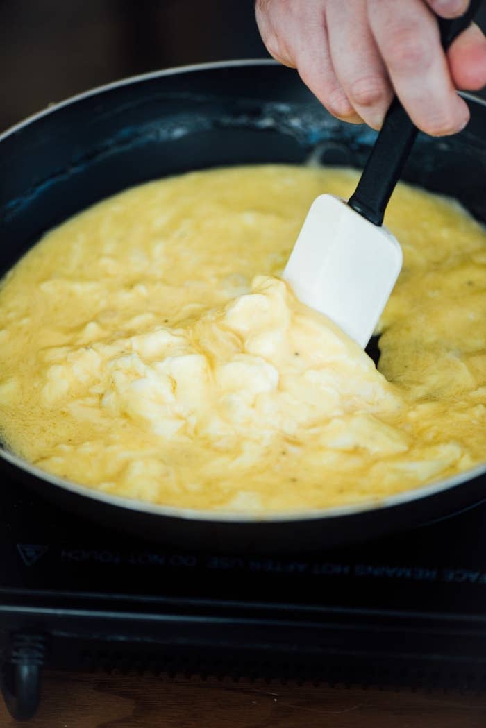 Someone scrambling eggs in a skillet.