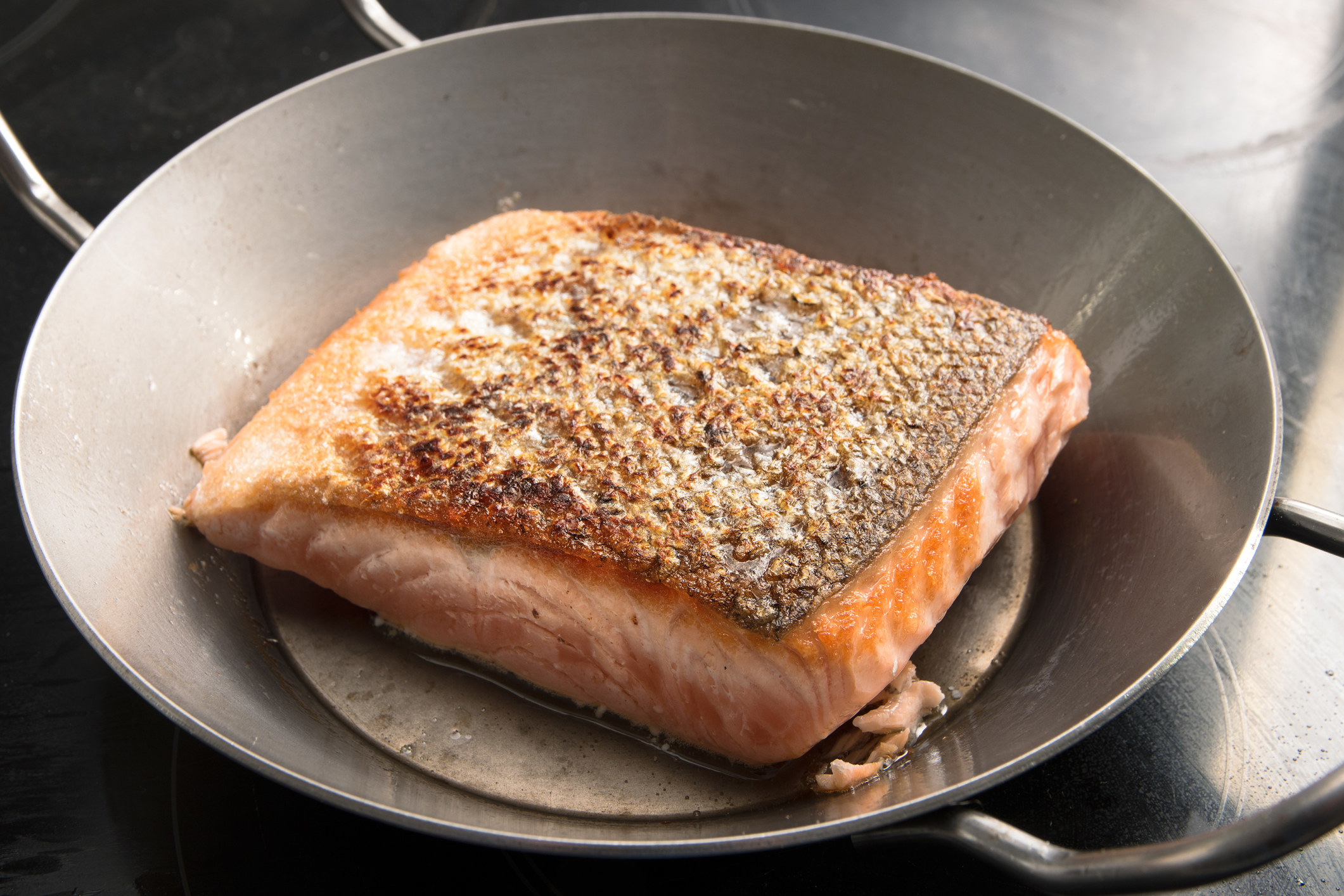 Crispy salmon skin in a pan.