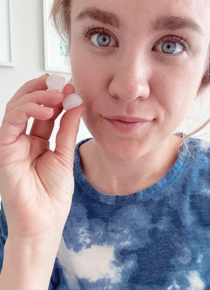 BuzzFeed editor holding up two silicone earplugs