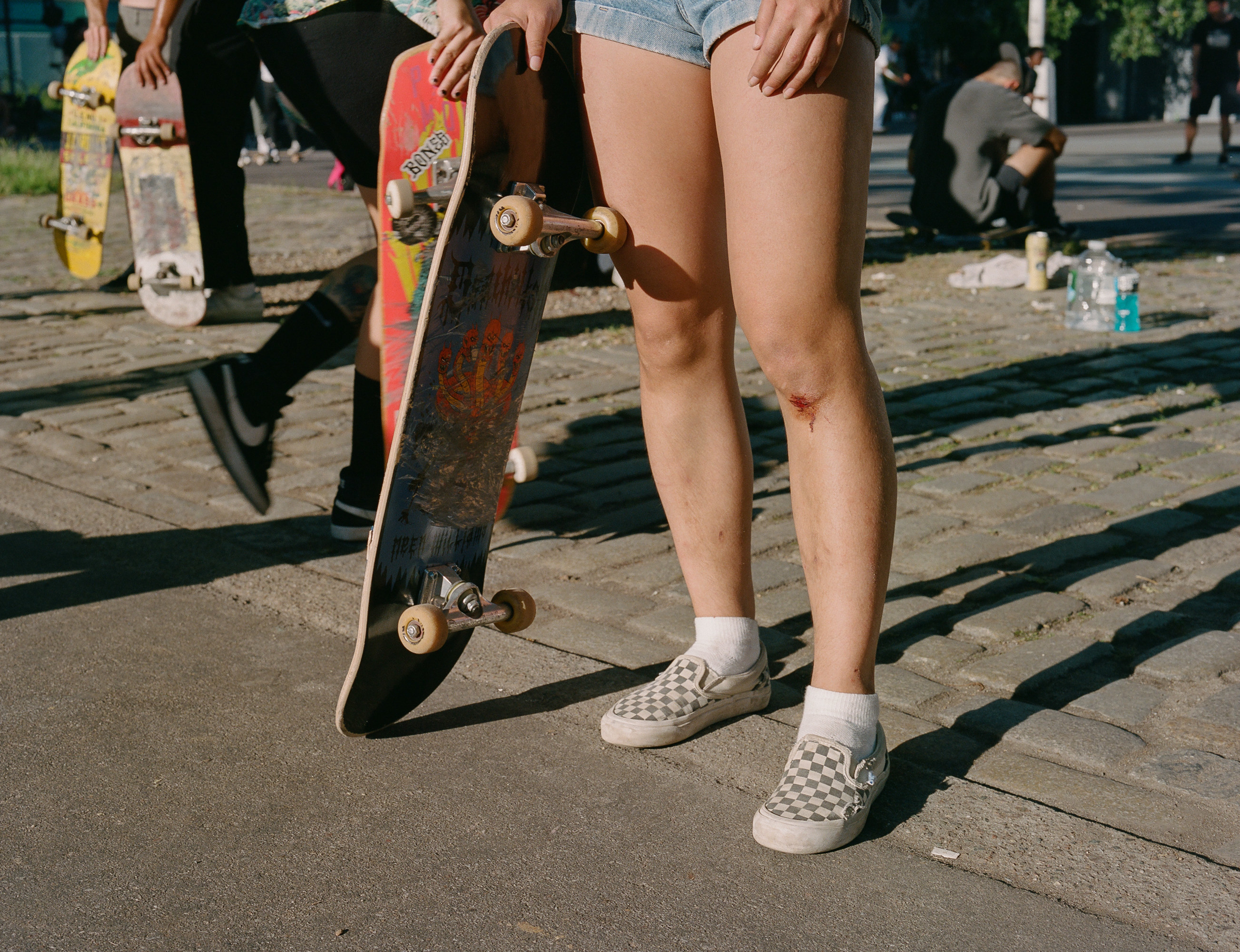 A woman with a cut knee and a skateboard 