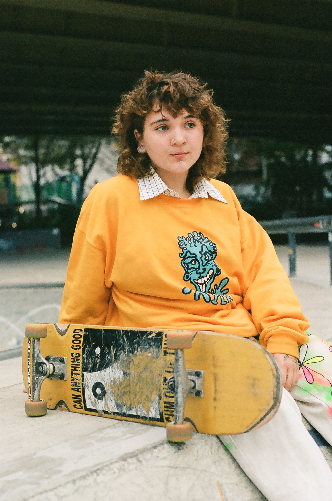 A woman with a yellow sweatshirt and a yellow skateboard