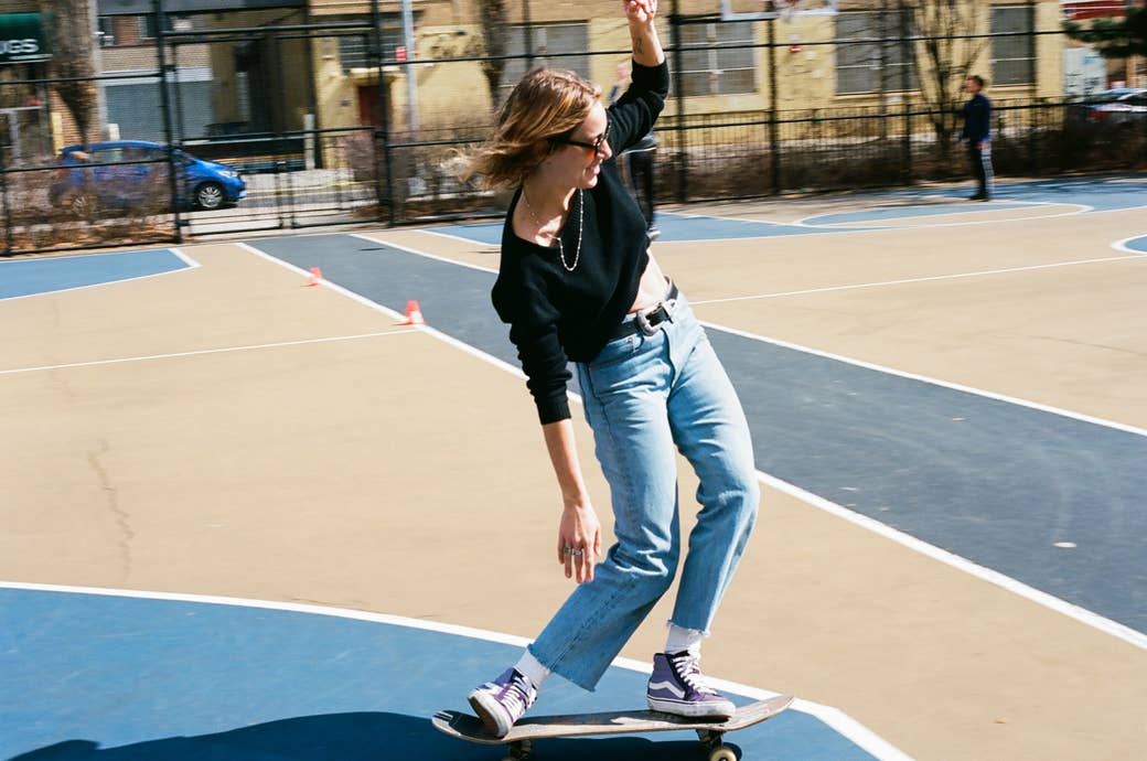 A woman on a skateboard with her hands up 