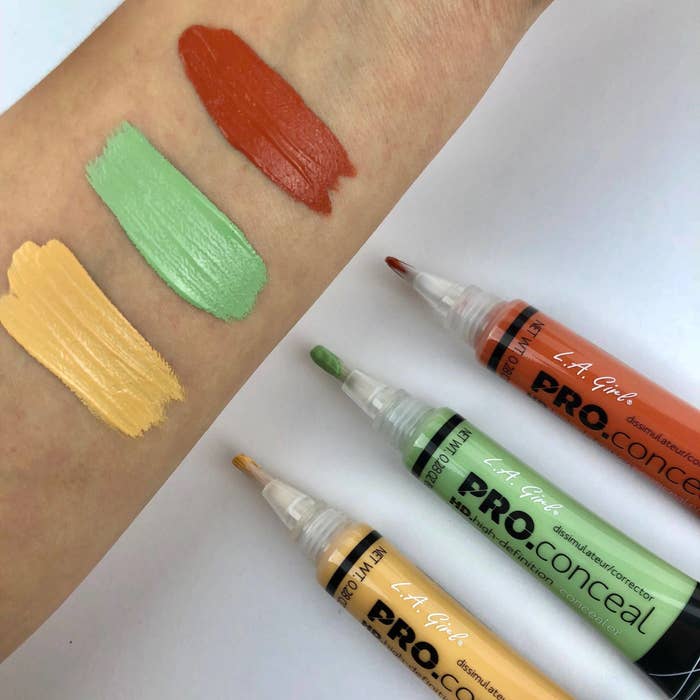 3 different colour corrector tubes in green, yellow and orange being swatched on a forearm