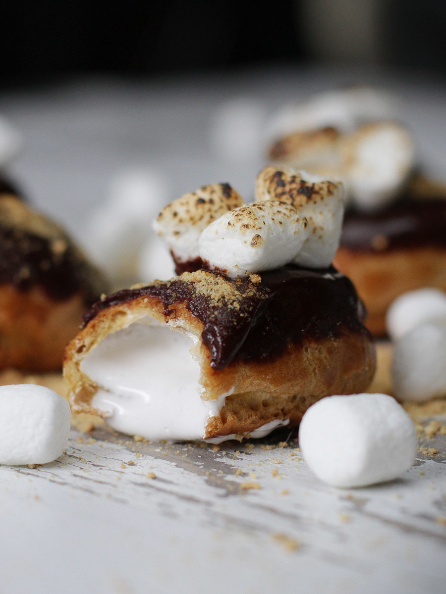 Mini éclairs filled with marshmallow fluff and topped with chocolate sauce, graham cracker sprinkled on top with toasted marshmallows