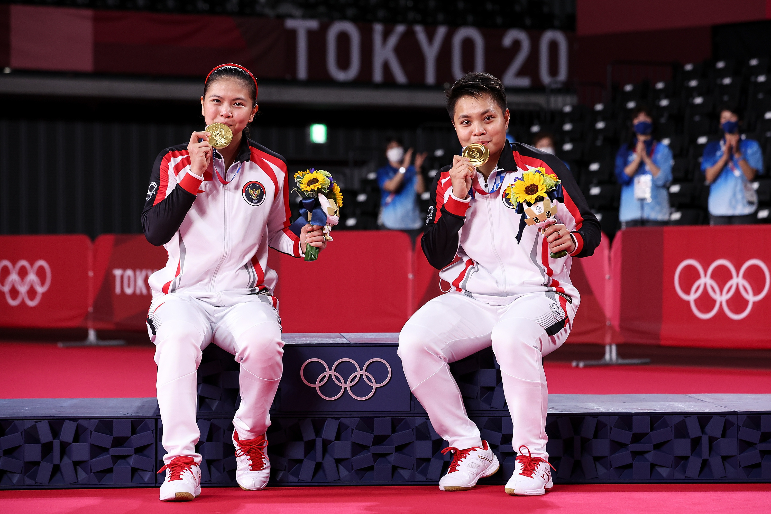 Greysia and Apriyani kiss their medals as they pose for photos