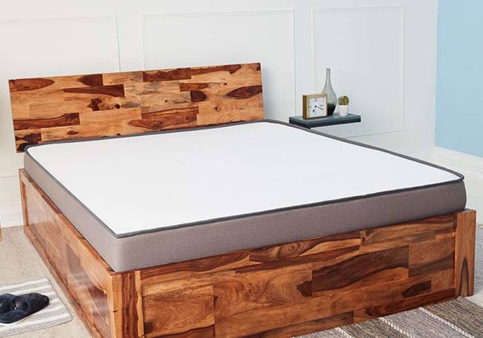 A Sheesham bed frame with a mattress on it