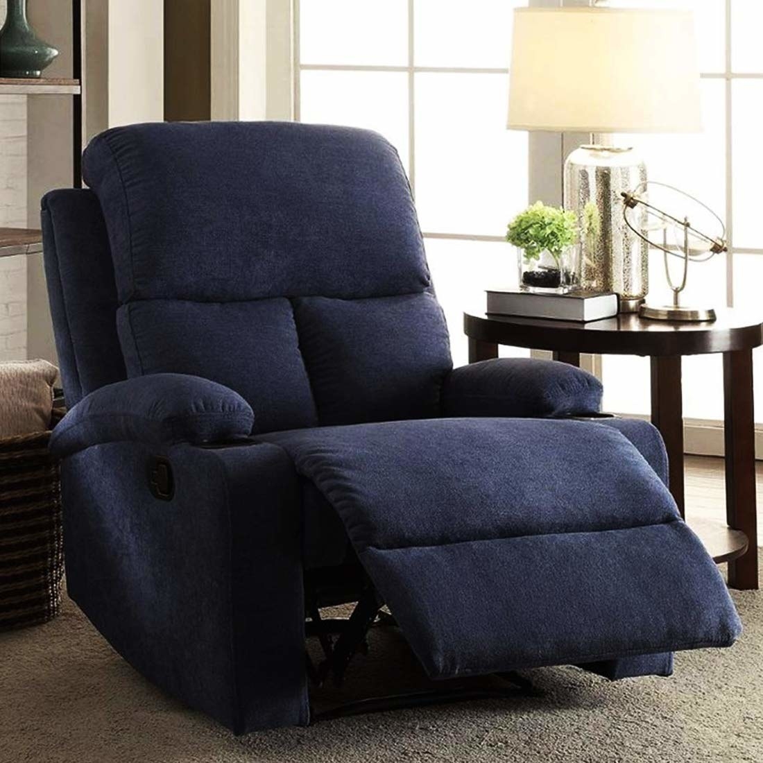 A blue recliner next to a side table with a lamp on it