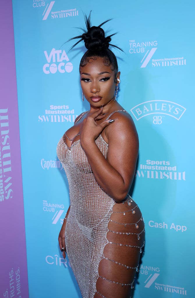 Megan posing at an event in a see-through dress with spaghetti straps