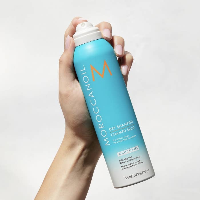 A woman holding a can of dry shampoo