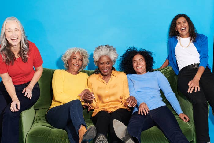 A group of women smiling as they sit on a couch