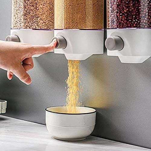 A person pressing a button on a grain dispenser to get desired amount in a white bowl