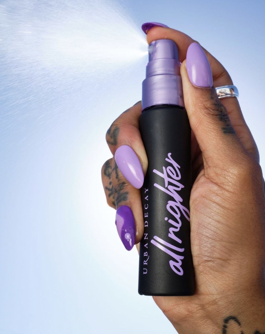 A woman holding a bottle of makeup setting spray