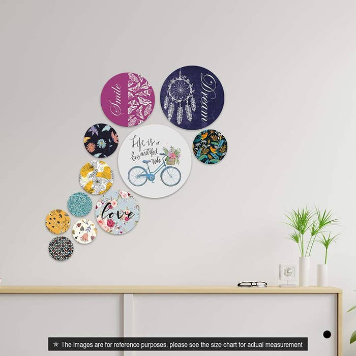Circular wooden boards on a white wall. They are colourful and have varied prints.