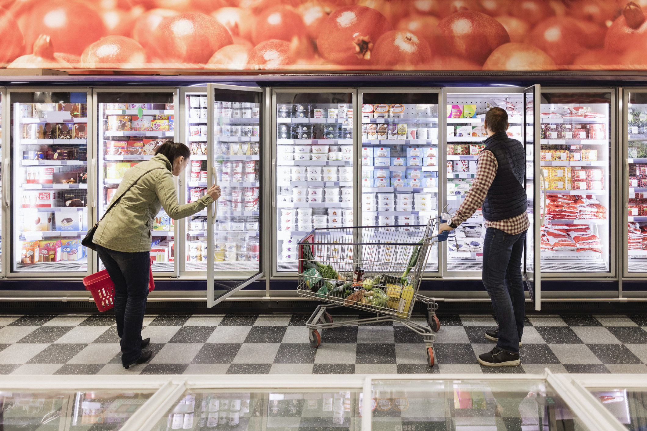 Two people shopping in the refrigerated aisle at the grocery store